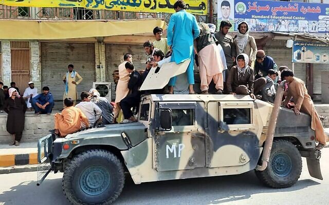 Таліби впереміш із місцевими мешканцями над броньованим автомобілем, захопленим у афганських сил безпеки