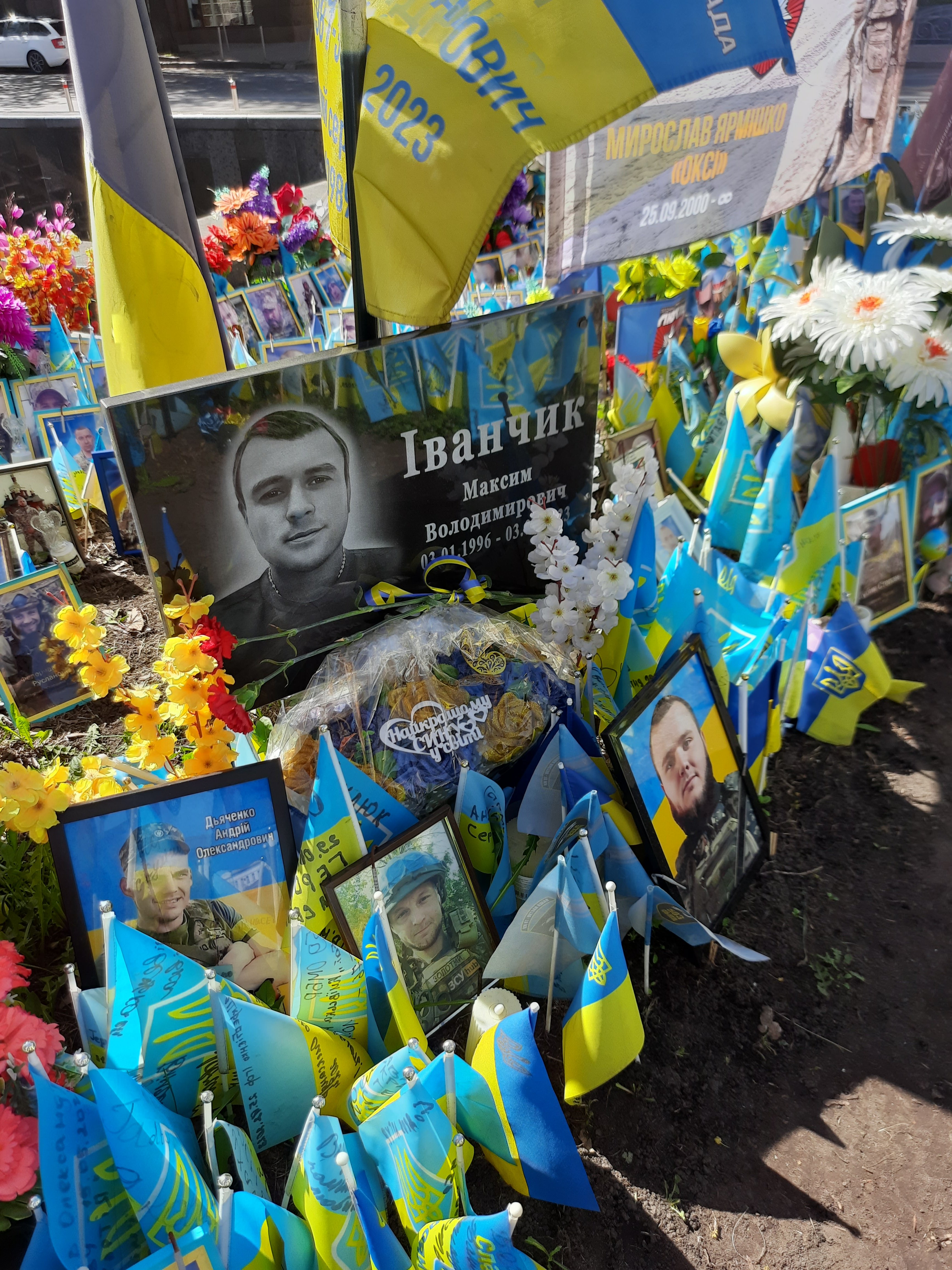 Гранітна плита з портретом воїна на тлі менших портретів і прапорців. Фото авторки