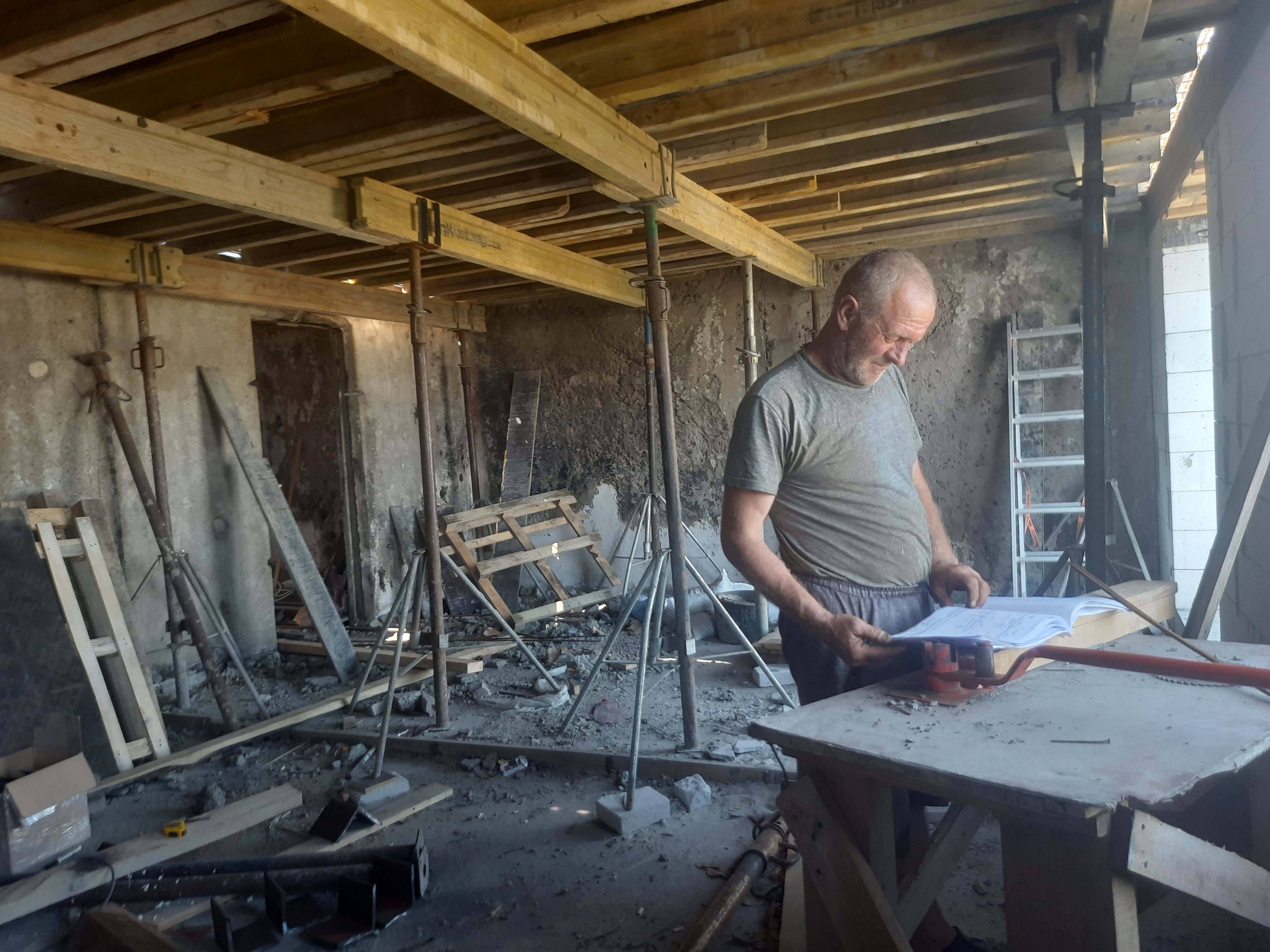 Будівельник у зруйнованій квартирі на дев'ятому поверсі. Вгорі — опалубка під бетонування нової покрівлі
