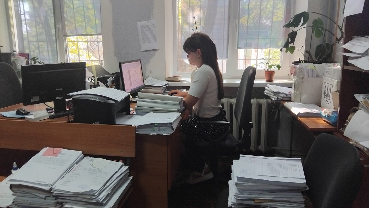 Помічниця судді Ольга Васюта за робочим столом. Саме вона бачить нову справу першою. Вона ж перевіряє, чи все з нею гаразд: чи не пропущені строки розгляду, чи все зазначено. «Якщо все ок, кажемо судді, що можна відкривати провадження. Далі справа йде до секретаря, він передає копії учасникам процесу». Фото Global Press Journal