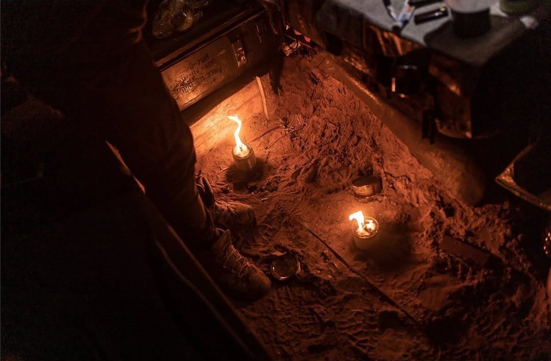 Soldiers warm themselves in a tiny dugout carved out of the forest near Kreminna (Luhansk region). Photo: Diego Herrera