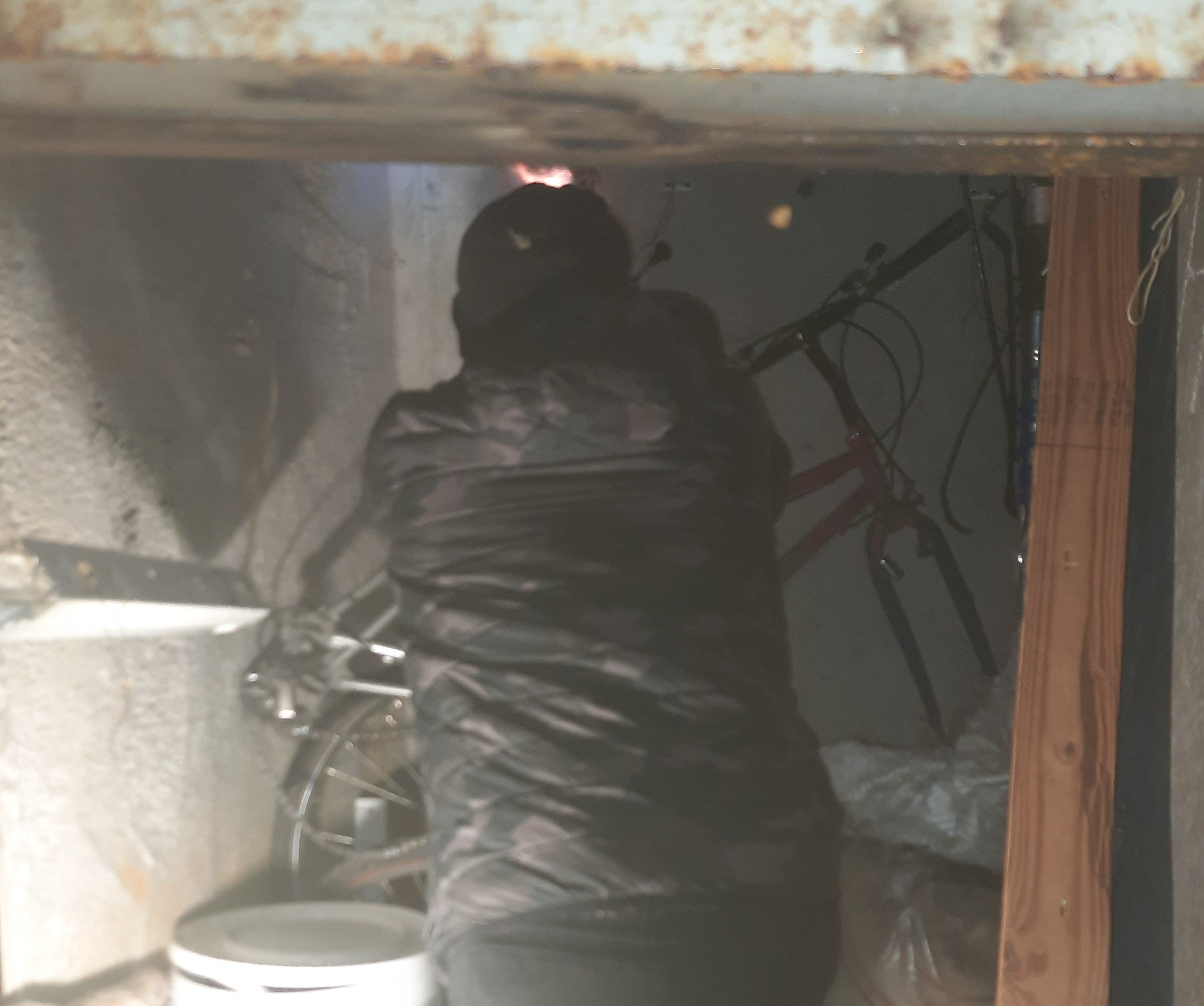 Чоловік із паяльною лампою лізе до труби в чужій щойно відімкненій комірчині