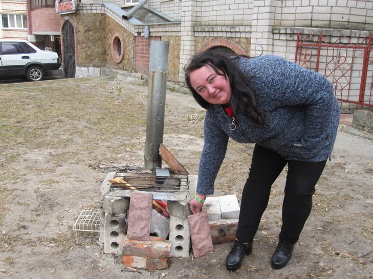 Наталя Теплякова біля саморобної пічки у дворі