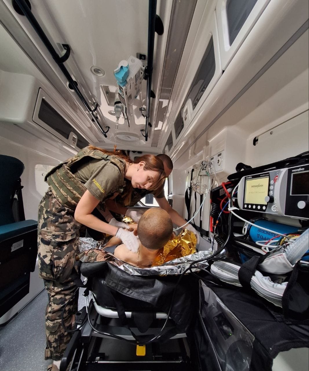 Volunteers from VMH-1 help a wounded soldier in one of the two emergency vehicles purchased with donations.