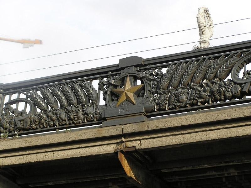 До 2021 року парапети мосту прикрашали серпи і молоти як невід’ємна конструктивна деталь. Парапети, як і міст загалом, на сьогодні мають статус пам’ятки
