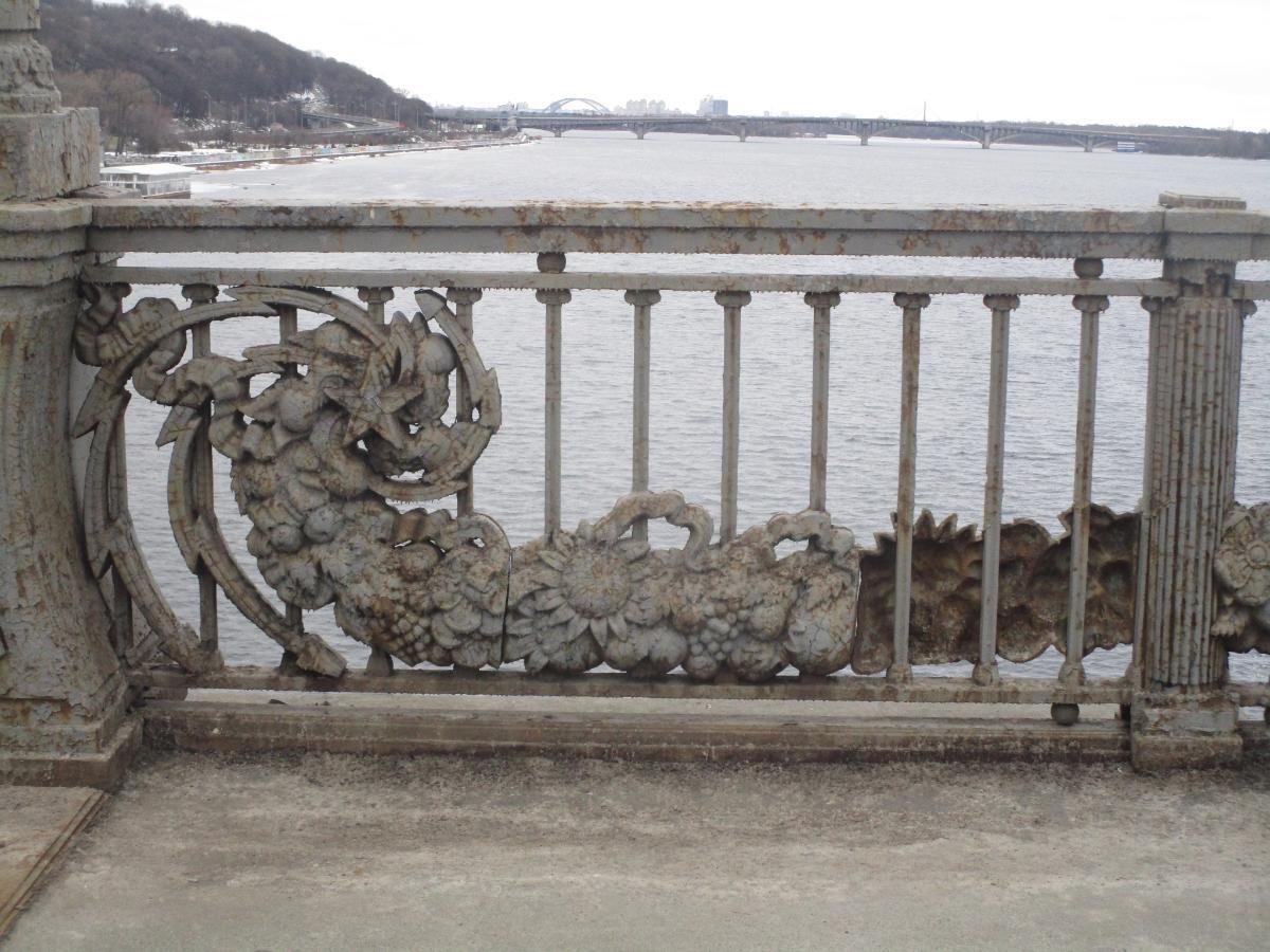 До 2021 року парапети мосту прикрашали серпи і молоти як невід’ємна конструктивна деталь. Парапети, як і міст загалом, на сьогодні мають статус пам’ятки