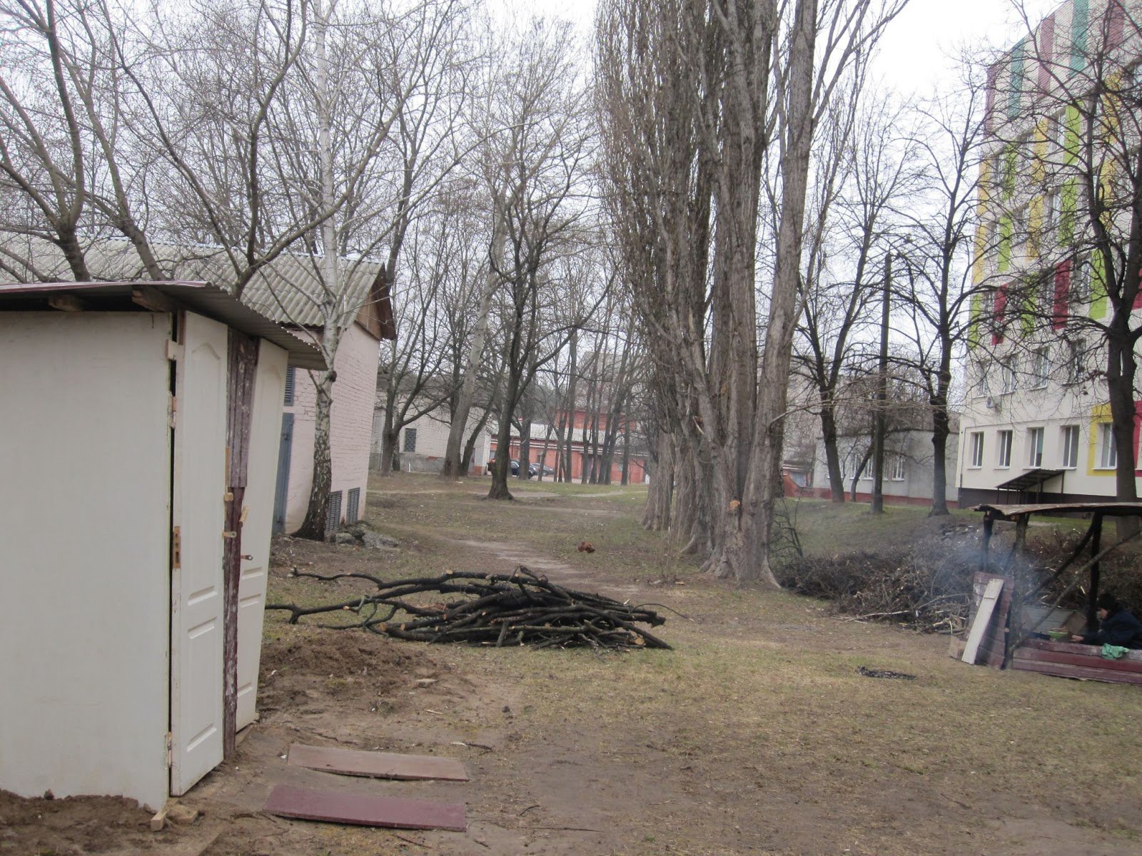 Двір пологового будинку. Зліва – нашвидкуруч зроблений вуличний туалет. Посередині – дрова для польової кухні. Справа – власне кухня