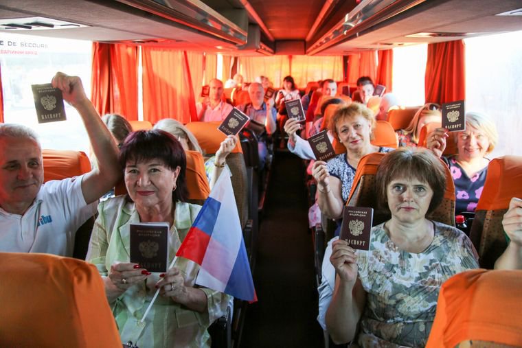 Люди демонструють свої російські паспорти, сидячи в автобусі до Росії, на зупинці в Донецьку, на Сході України, 27 червня 2020 року. Фото: AP