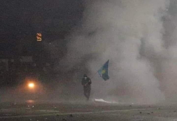 Активист Берик Абишев спасает флаг Казахстана во время разгона мирной демонстрации в Алматы 6 января. Абишев выжил, но был ранен и нуждается в операции, на которую собирают деньги в Фейсбуке. Фото очевидцев, предоставлено автором